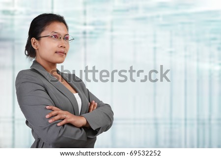 South East Asian businesswoman looking away to empty space with blur glass windows as background.