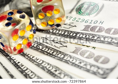 Two dices on top of several one hundred dollar bills