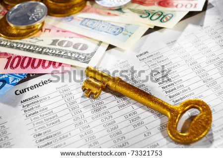 Golden key over the foreign exchange sheet with money from different countries on edge