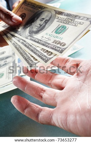 Two people on money exchange, taken close up, with one hand handing over US dollar bills