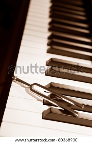 Tuning fork on top of piano keys in sepia color