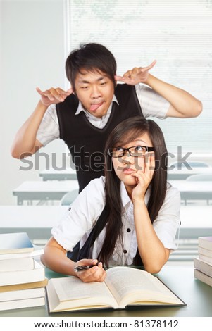male student mocking and bothering the female student in class