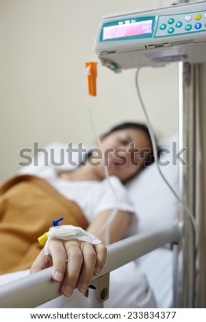 IV drip machine with patient in the hospital. Focus on the patient hand