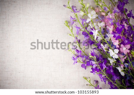 Art background with bright purple wild flowers on linen fabric