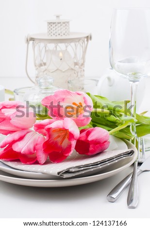 Festive spring table setting with pink tulips, napkins in bright colors