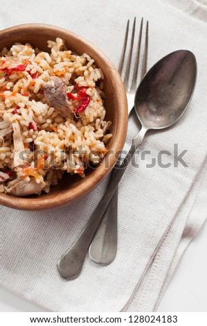 Natural food: rice with meat and vegetables in a wooden bowl with vintage cutlery on a linen napkin