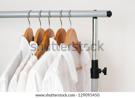 White clean clothes, shirts and jackets hanging on a rack in a row