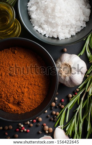 Fragrant spices, rosemary, allspice, garlic, oil and salt on a black background, culinary still life