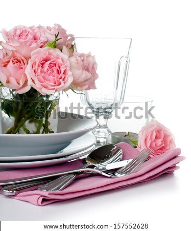 Luxurious table setting with pink roses, candles and shiny new cutlery on a white background, isolated