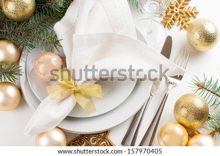 Festive Christmas table setting, table decorations in gold tones, with fir branches, baubles, decorations.
