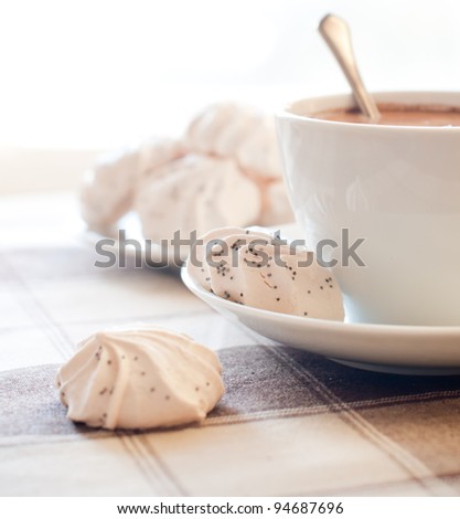 A cup of coffee and meringues on brown cloth