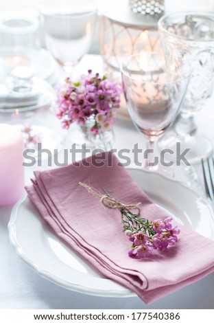 Festive wedding table setting with pink flowers, napkins, vintage cutlery, glasses and candles, bright summer table decor.
