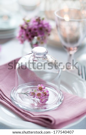 Bouquet of pink flowers in a glass bell jar on a festive wedding decorated table, a bright summer table decor.
