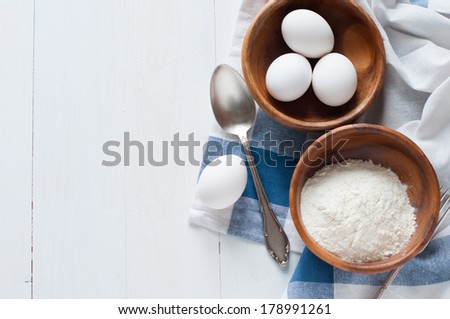 Natural healthy food, flour, eggs, cutlery and linen napkin on a white wooden board, baking and cooking background, rustic style