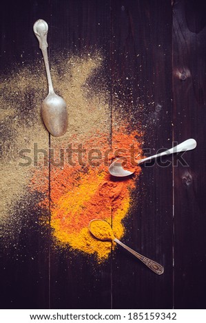 Bright spices and spilled curry powder, allspice, paprika and spoons fell on the wooden board