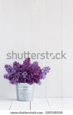 Bouquet of beautiful spring flowers of lilac in a vase on a white vintage wooden board, home decor in a rustic style