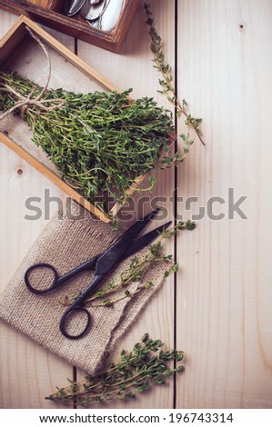 Rustic home kitchen still life, dried herbs, old boxes, antique cutlery and vintage scissors on a wooden table.