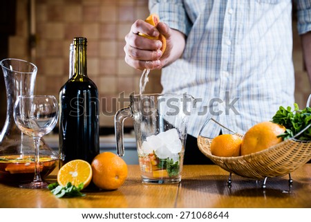 The man squeezes grapefruit juice in a decanter for making home sangria for home party, home kitchen interior.