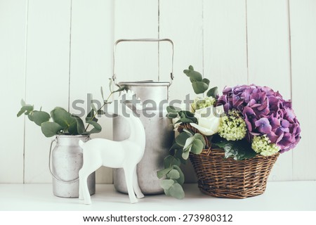 Big bouquet of fresh flowers, purple hydrangeas and white roses in a wicker basket and a rustic home decor on a shelf in the interior, vintage style