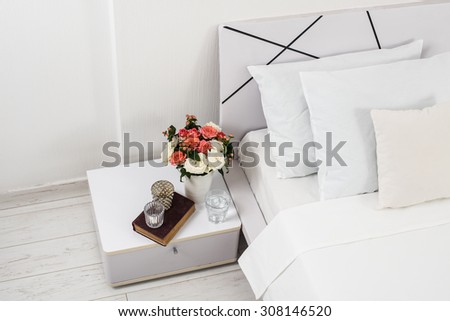 Interior of white bedroom, new linens on the bed, the room at the hotel. Bedside table decor and pillows closeup.
