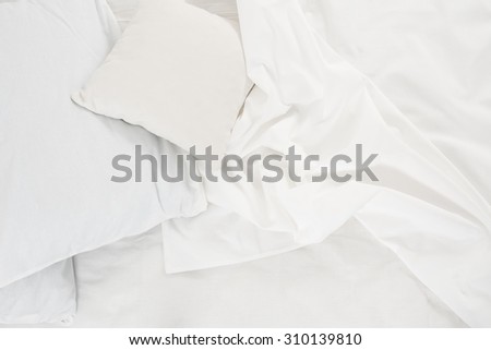New snow-white bed, pillows and crumpled sheets, white linen cloth, white abstract background.