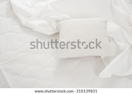New snow-white bed, pillows and crumpled sheets, white linen cloth, white abstract background.