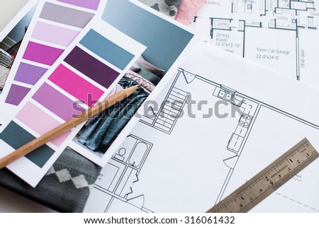 Interior designer\'s working table, an architectural plan of the house, a color palette, furniture and fabric samples in grey and pink color. Drawings and plans for house decoration.