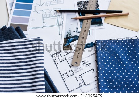 Interior designer\'s working table, an architectural plan of the house, a color palette, furniture and fabric samples in blue color. Drawings and plans for house decoration.
