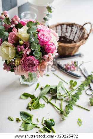 Just created bouquet of fresh flowers and leaves, scissors on a table, florist\'s studio.