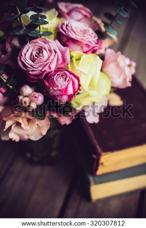 Elegant bouquet of pink flowers and ancient books on an old wooden board with copy space. Vintage decor.