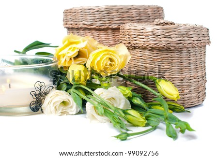 Two wicker boxes, candles and a bouquet of yellow flowers on a white background