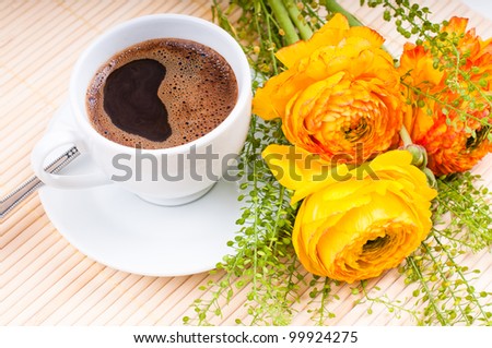 cup of freshly brewed coffee and flowers on the table