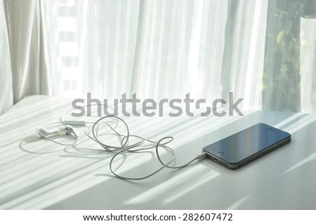 Smartphone with earphone on White table.