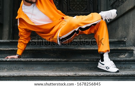 Closeup photo of a young man in bright streetwear dancing hip hop on the stairs in a row building. Professional street dancer dancing break dance on the street. Cropped photo. Background. Photo stock © 