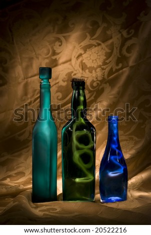 Three colored bottles lit creatively to contain the light against a dramatic golden background.