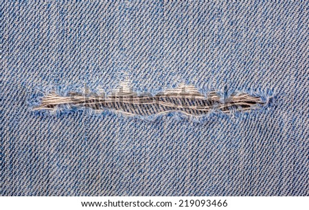 The torn old blue jeans texture with a hole and its background