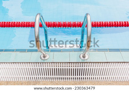 The metallic ladder for using entrance to swimming pool, close with red marked lanes.