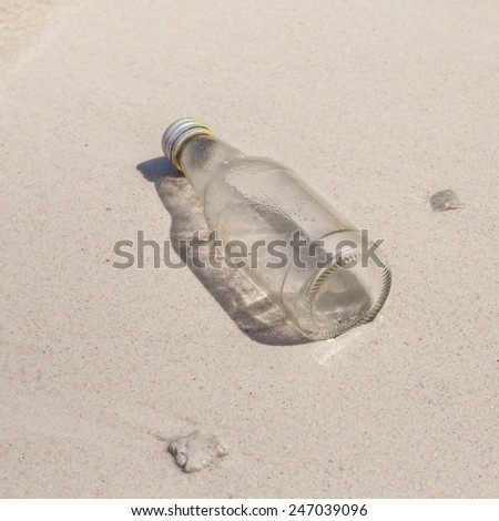 Glass bottle and small corals on beach sand, environment problem needed to urgent help.