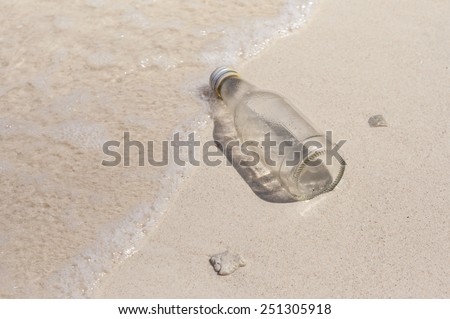 Glass bottle and small broken corals washed up as rubbish on a beach, garbage on beach, concept of beach environment.