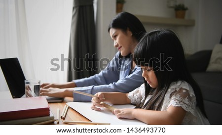 Photo of Family concept. Mom is working and taking care of her daughter too.