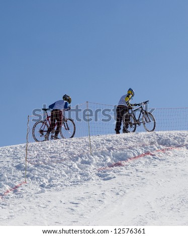 Couple of professional winter bikers in mountains Tien Shan at contest (series sport, mountains, extreme, horses, teenagers)