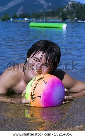 Teenager with variegated ball on the beach in summer vacation at Borovoe lake in Kazakhstan (series Teenagers)