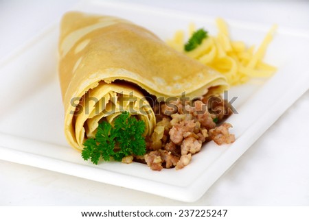 Crepe with ground meat and parsley on white square plate, isolated