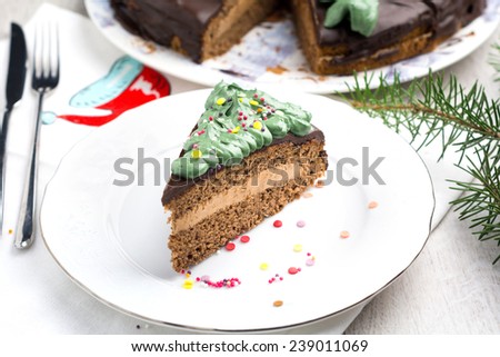 Chocolate cake with chocolate butter cream filling and dark chocolate glaze decorated with green frosting and confetti for Christmas or birthday on white plate (Prague chocolate cake)