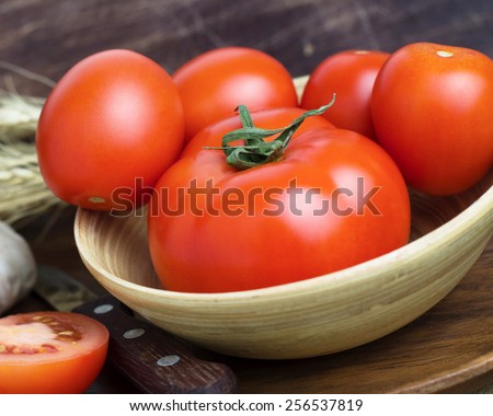 Still life of tomatoes: fresh organic tomatoes, garlic and wheat ears with wooden props close up, rustic style