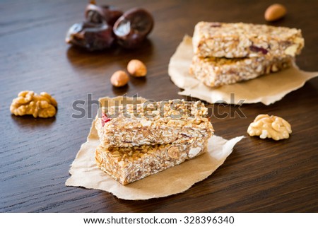 Granola bar or energy bar with oats, dates and nuts on brown wooden background