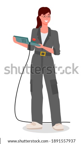 Girl mechanic dressed in a special uniform gray work overalls, holding control panel from the machine isolated on white. Modern woman in the male profession, car service worker or factory engineer