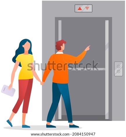 Couple enters modern elevator with iron doors. Lifting mechanism of elevator with up and down buttons. Passengers walk into door of lift. Metal lift for transporting people between floors of building