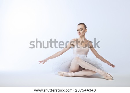 beautiful and plastic ballerina in tutu sitting on the floor, a ballet performance