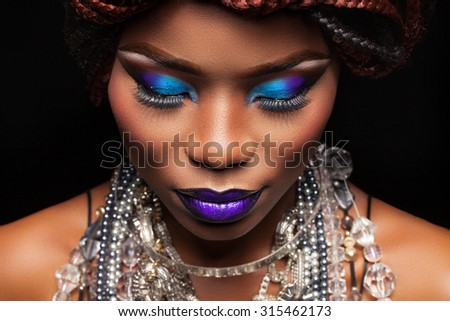 large frame female face with dark skin and bright makeup